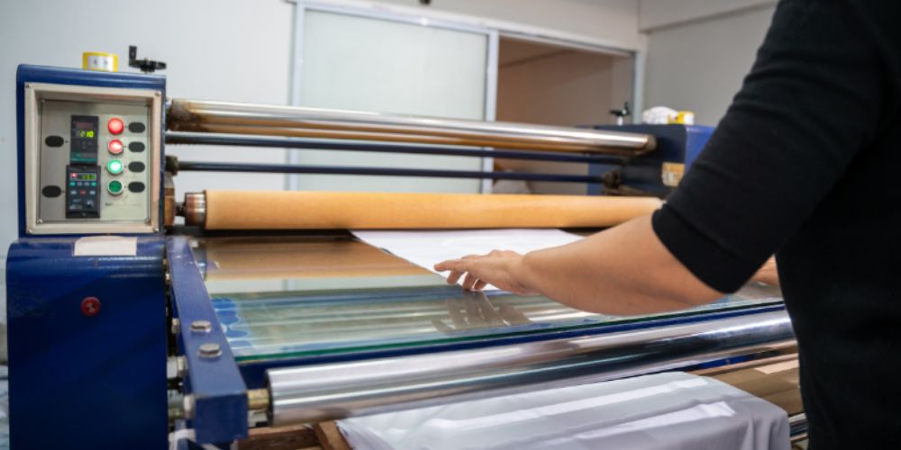 A person pushing fabric through a textile manufacturing machine.