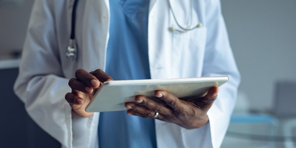 A clinician updates medical records on a hand-held tablet device.