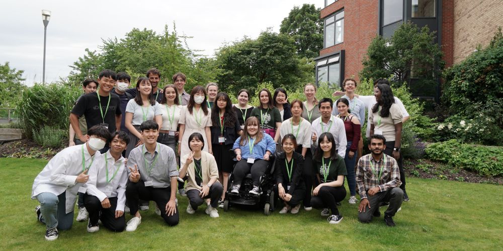 Group of KAIST and Leeds students smile and laugh for a group photo on the grass