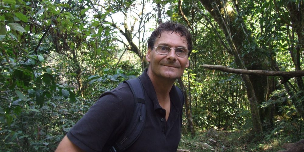 Professor Jon Lovett in the Tanzanian forests, wearing a navy polo shirt and looking at the camera.