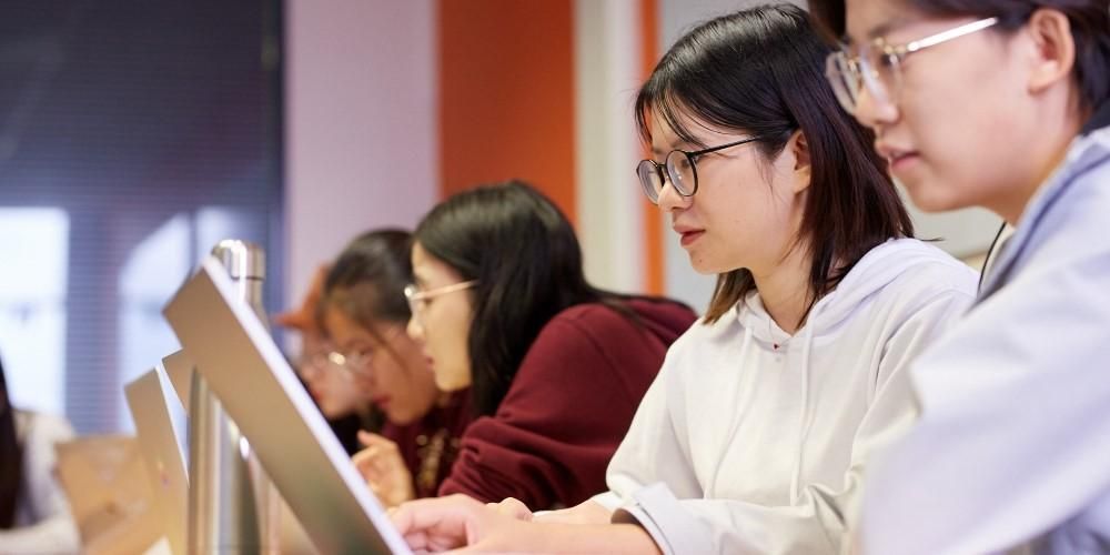 Four students sat in a row working on tablets