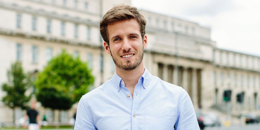 A Masters student stood in front of the Parkinson Building