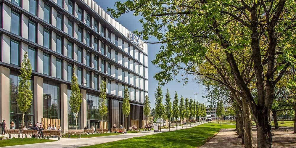 Facade of the Nexus building with a tree lined seating area.