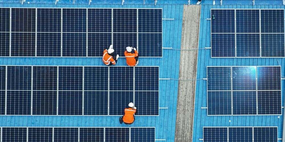Overhead shot of workers in high-vis and hard hats working on solar panels.