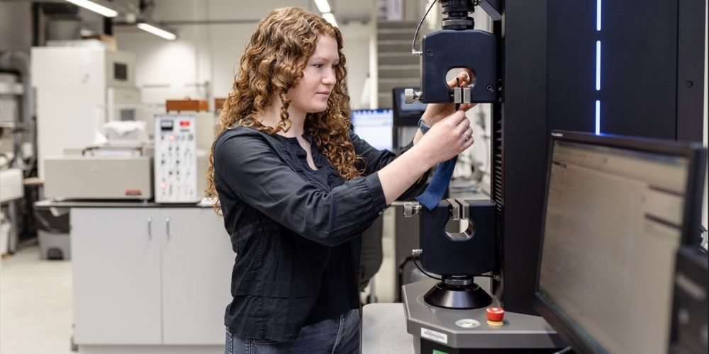 A student testing denim stretch in a machine in the Testing Lab School of Design.