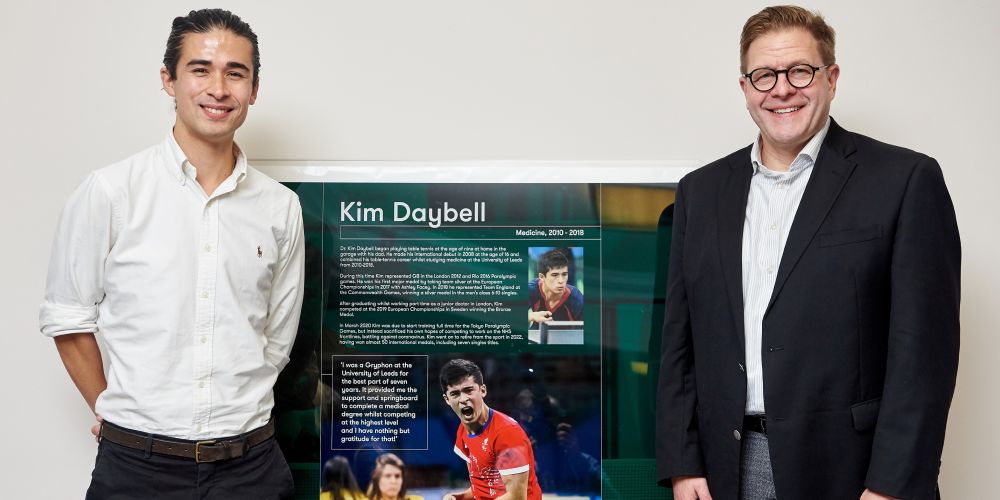 Kim Daybell and Jeff Grabill stand beside the poster to induct Kim into the Leeds Sport Hall of Fame