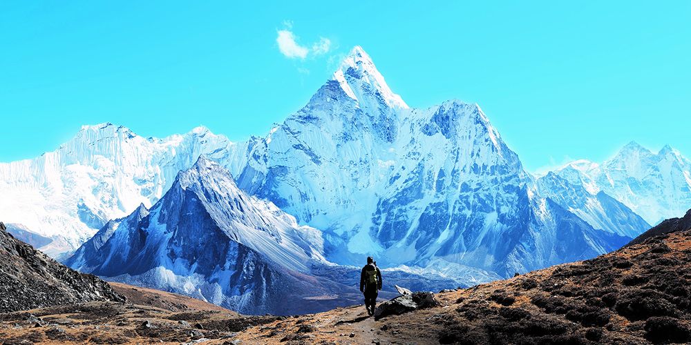 A mountain with a hiker walking towards it