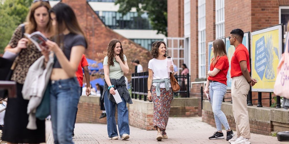 Two student ambassadors stood outside the Leeds University Union building, welcoming a couple of open day visitors