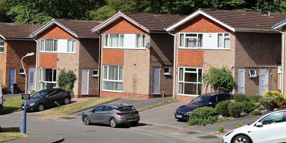 A row of newly built detached houses on a suburban street in the daytime.