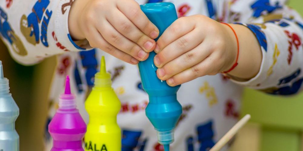 A child squeezes a paint bottle.