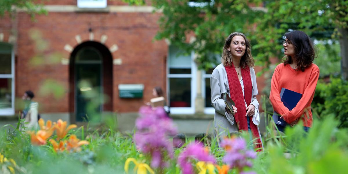 Postgraduate students outside Clothworker&#039;s Court with bright flowers in the foreground