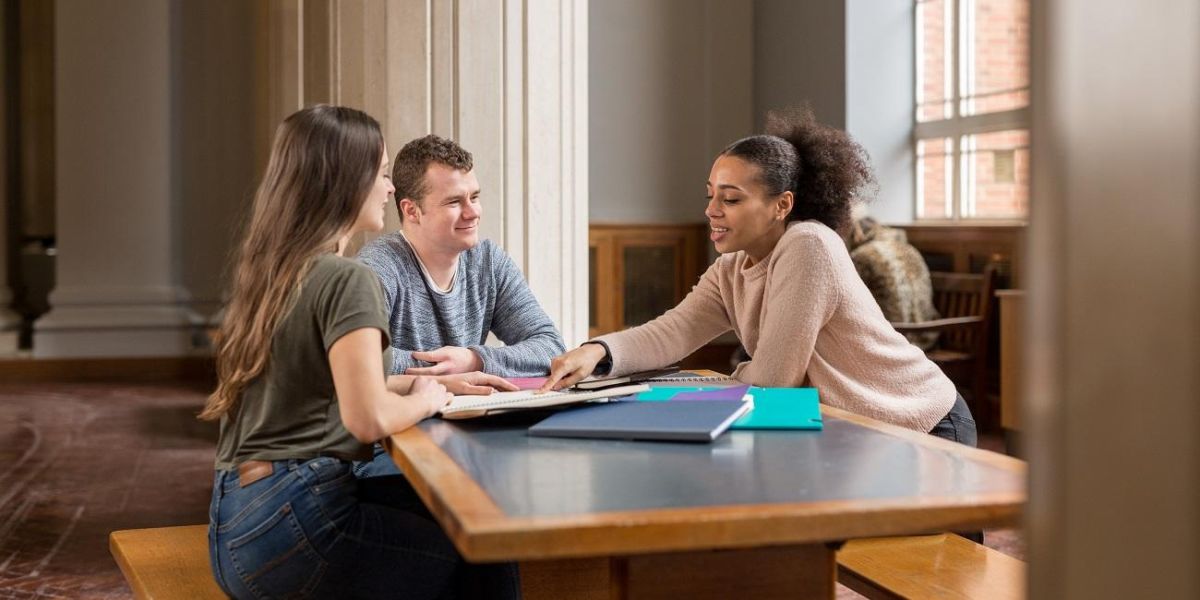 A group of students sat at a table in Parkinson Court, chatting and studying