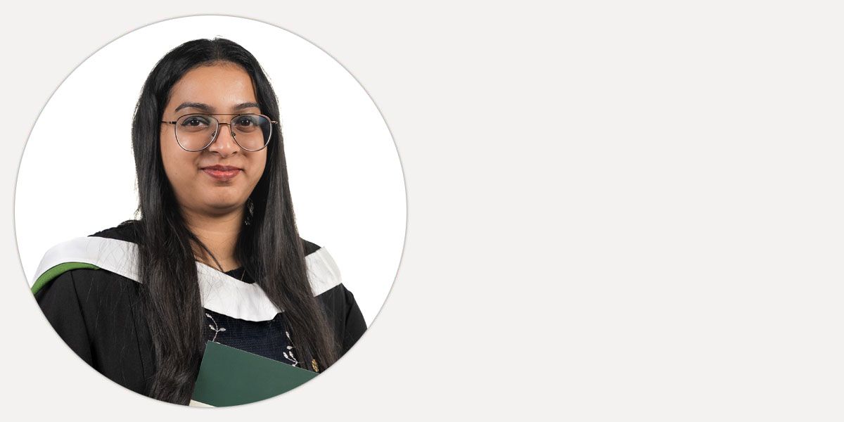 Anju rajan, smiling in graduation gown.