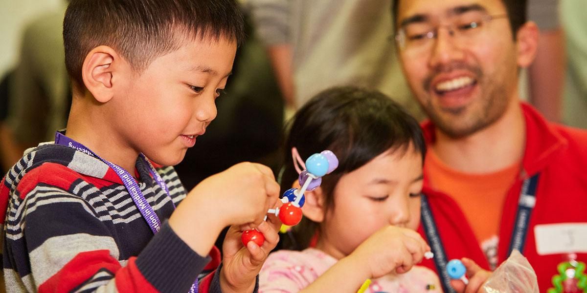 Two children building DNA models supervised by an adult