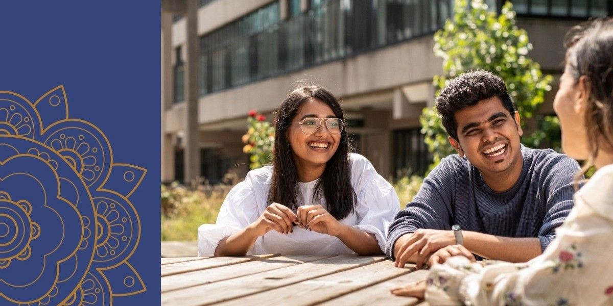 Three students sit smiling and laughing together on an outdoor table. Next to the image is a blue stripe with a gold mandala pattern.