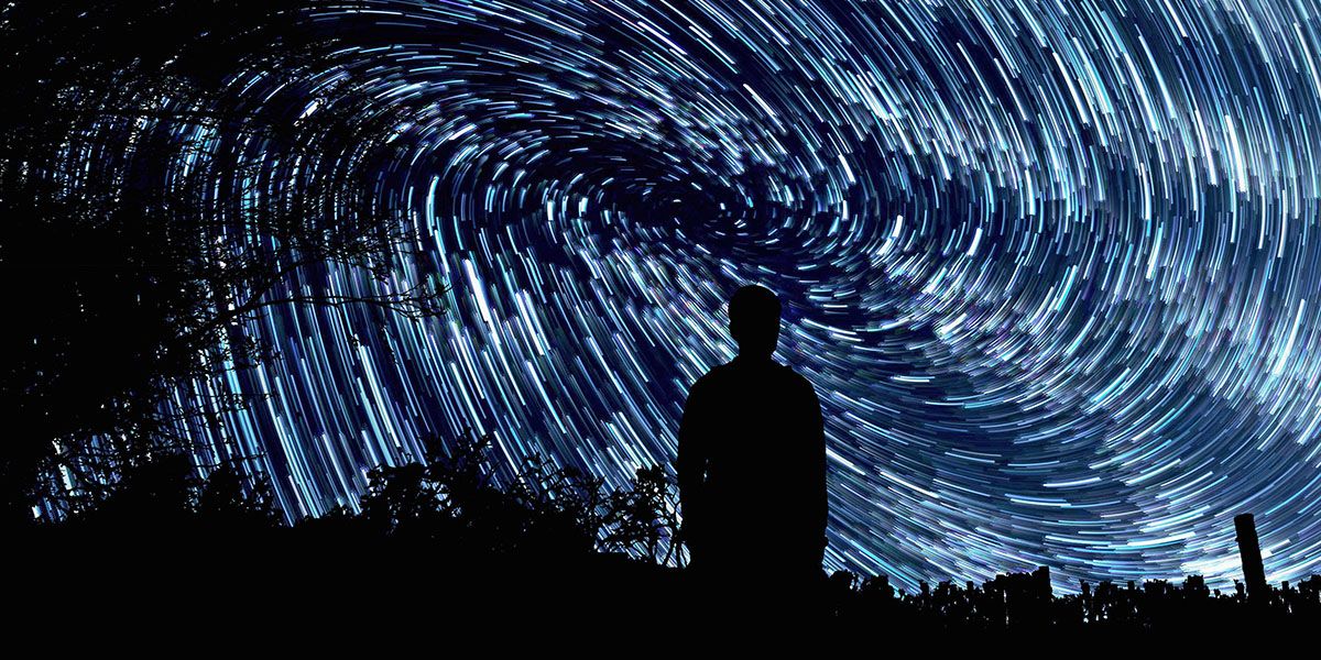 Star trails in a night sky. A person is looking into the sky.