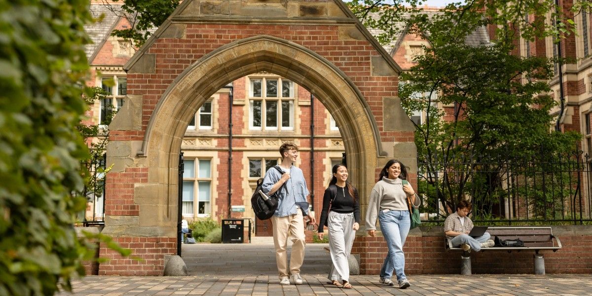 Three students walked beneath the clothworker's arch.