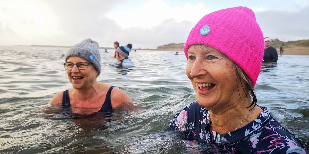 Two older people swimming in the ocean.