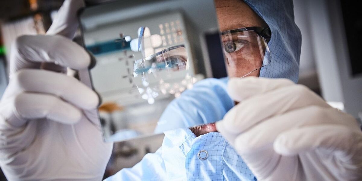 Researcher in the nanotechnology cleanroom looking at a slide with gloves on