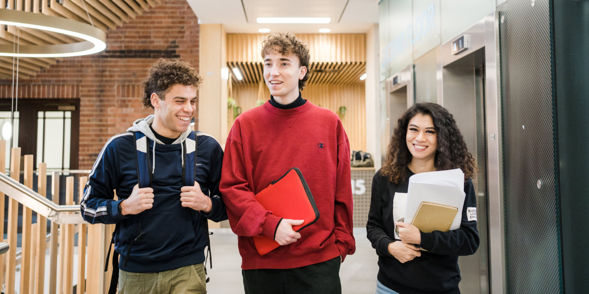 Three students walk through a corridor in the Sir William Henry Bragg building.