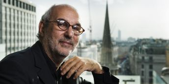 Alan Yentob profile image, sat at a window with a view of London in the background