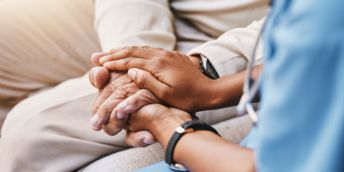 A medical professional holds a patient's hands
