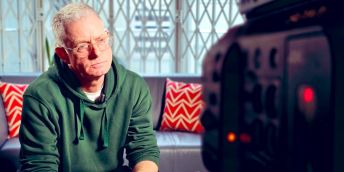 Andrew Hartle sits speaking to a television camera