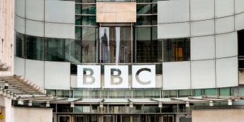 The BBC logo on Broadcasting House, a large, curved, glass-fronted building