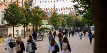 Students walk through the University of Leeds campus with bunting strung between buildings.