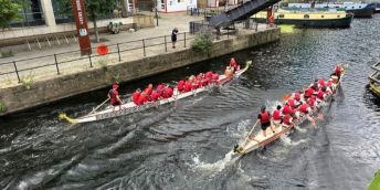 Two dragon boats racing down Leeds Dock