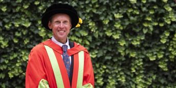Jack Maitland stands in academic gown and dress