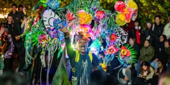 A performer wearing a colourful carnival costume dances at Light Night Leeds 2025.