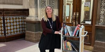 Lou is pictured with a trolley of books in Leeds City Library