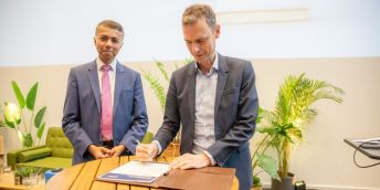 Masud Khokhar and Jeroen Geurts both wearing suits signing a document.