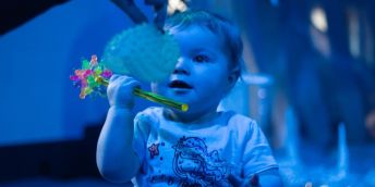A baby smiles while looking at a lit up ball