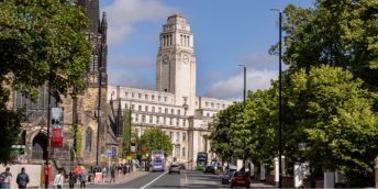 A view up the hill on Woodhouse Lane towards the Parkinson Building, with students, buses and cars.