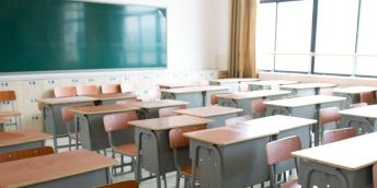 An empty classroom showing a wall with windows
