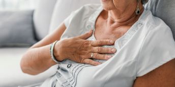 An older person holds on to their chest in pain