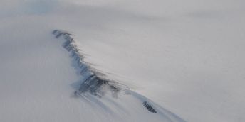 White expanse of snow with grey rock ridge breaking through