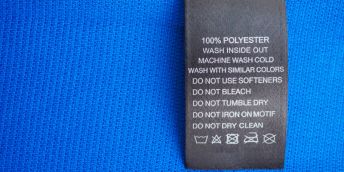 Black laundry care washing instructions clothes label on blue jersey polyester sport shirt