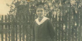 An old photograph of Ivy Angerer, standing in front of fence railings.