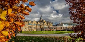 Leeds University Business School with autumnal trees in the foreground.