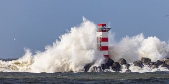 Lighthouse on the south pier in IJmuiden, Netherlands, being struck by big breaking waves caused by the storm Dudley in february 2022