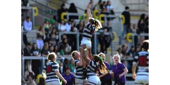 Leeds women's rugby union players are reaching for the ball in a line-out in their varsity match against Leeds Beckett at Headingley Stadium.