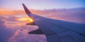 the wing of an aeroplane as viewed from the cabin at sunset