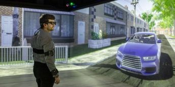 A person wearing virtual reality equipment stands in the University of Leeds' Highly Immersive Kinematic Experimental Research lab