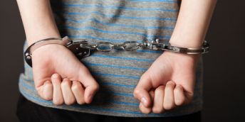 A child's arms in handcuffs