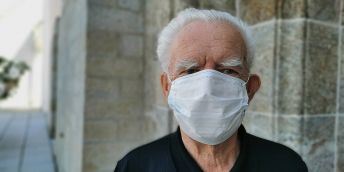 An elderly man wearing a face mask over his nose and mouth