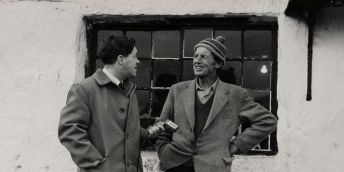 A mid 20th century picture showing a researcher holding a microphone in front of another person.