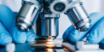 A scientist looking at slides through a microscope